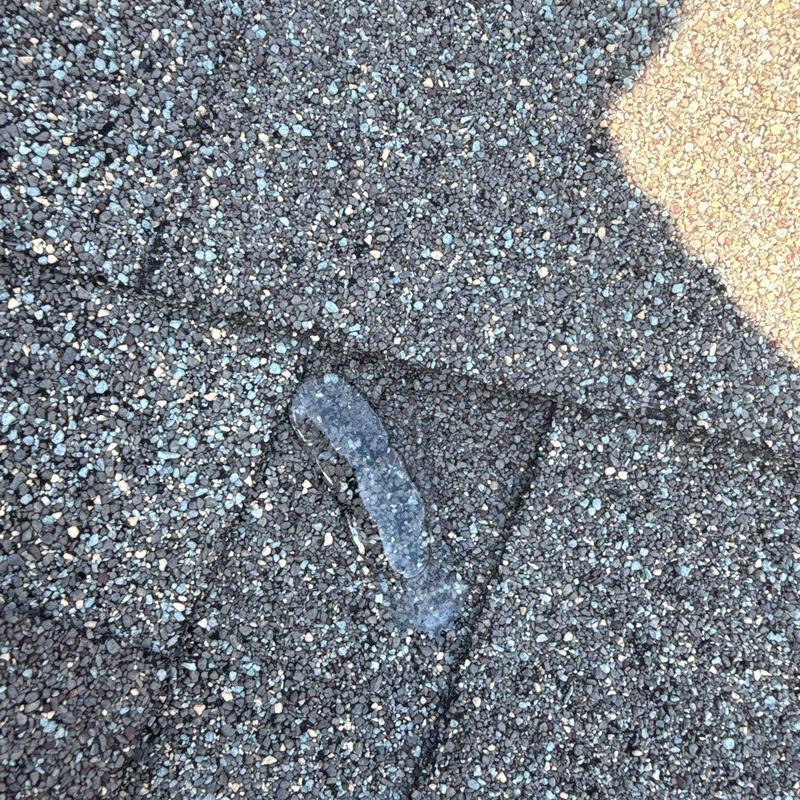 Asphalt shingle roof with damaged granules and sealant spot