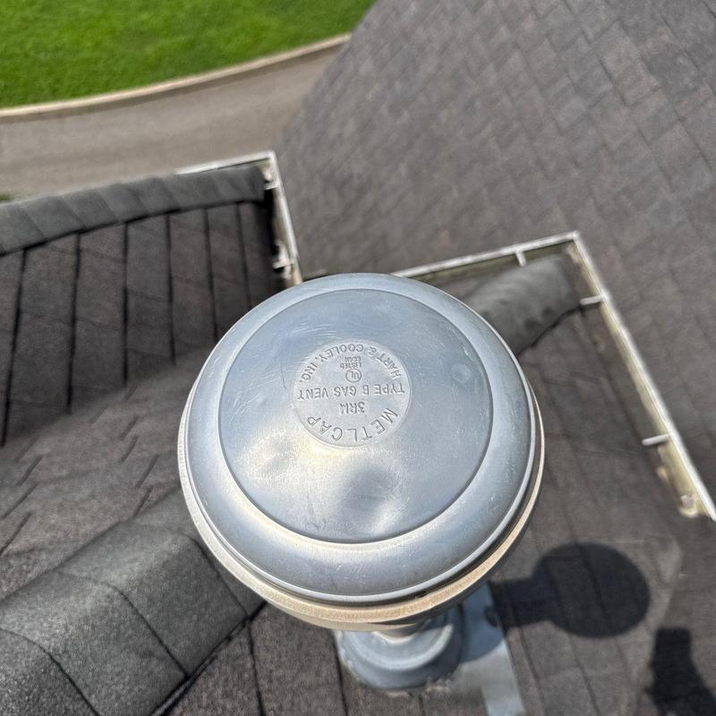 Metal B gas vent cap showing dents on asphalt shingles
