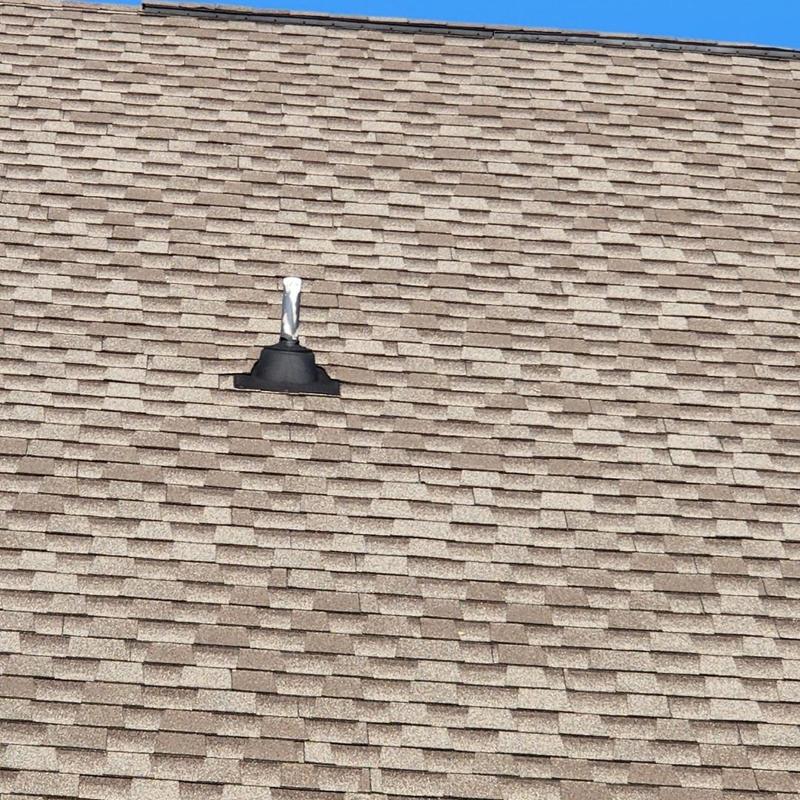 Asphalt shingles with storm damage near vent pipe