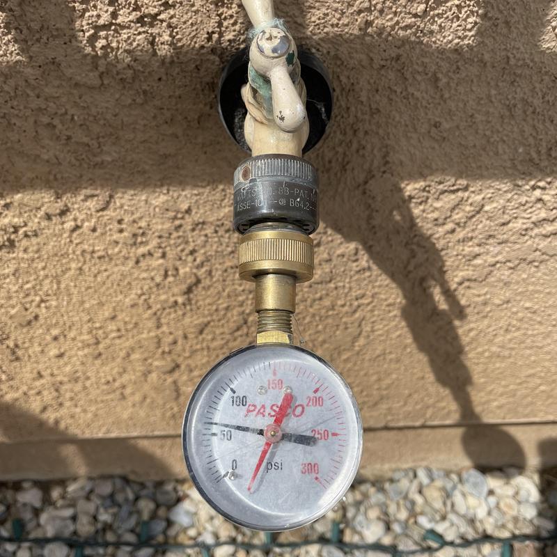 Water pressure gauge attached to outdoor hose bibb valve
