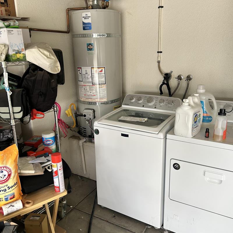 Water heater and washer with cleaning supplies in garage