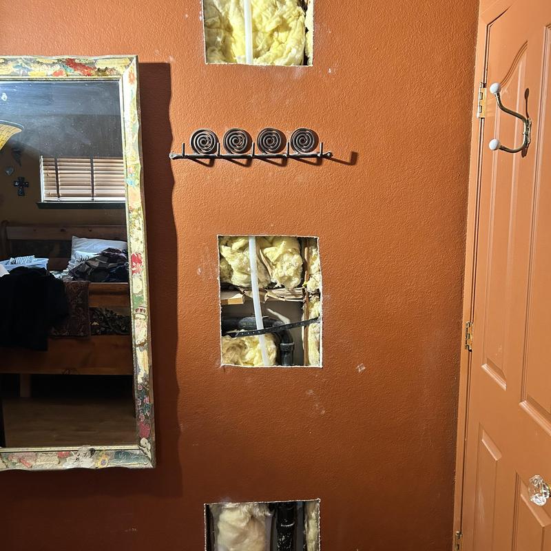 Copper pipe leaks exposed in drywall wall cutouts