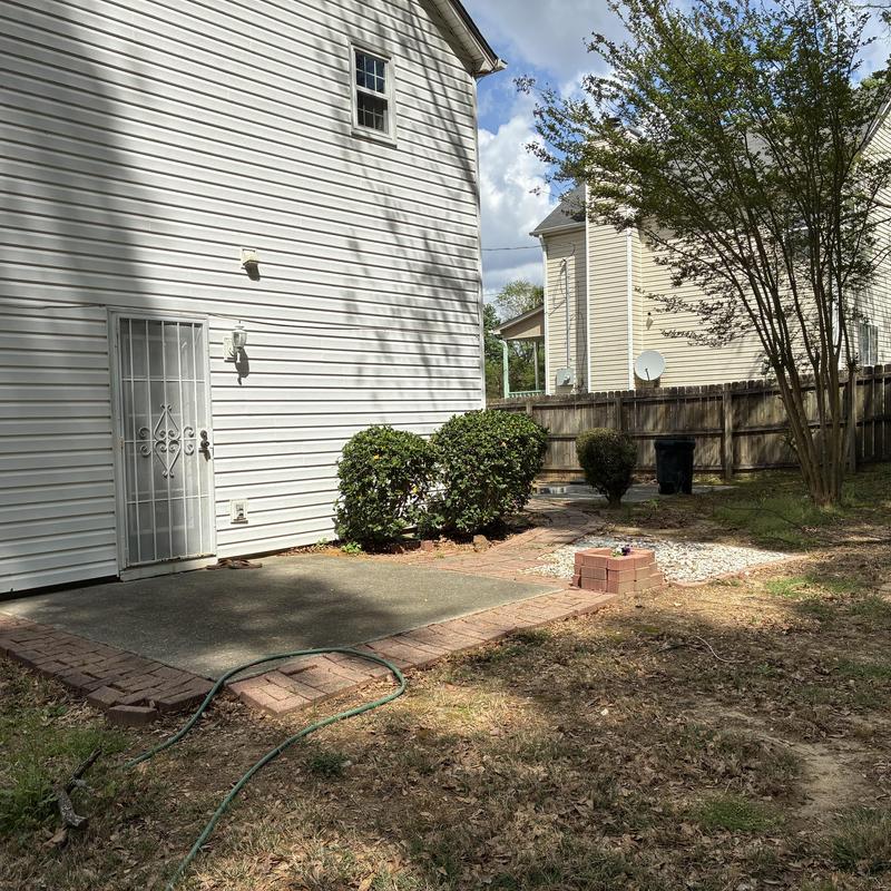 10' x 10' Rear concrete pad with brick edging and bushes