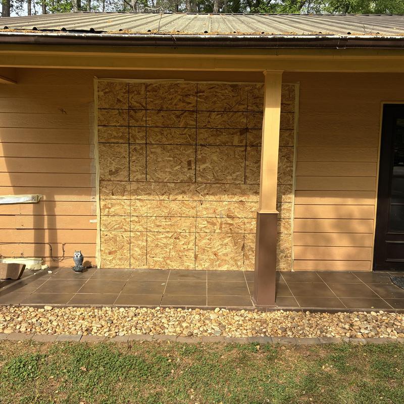 Exterior window boarded with plywood on house facade