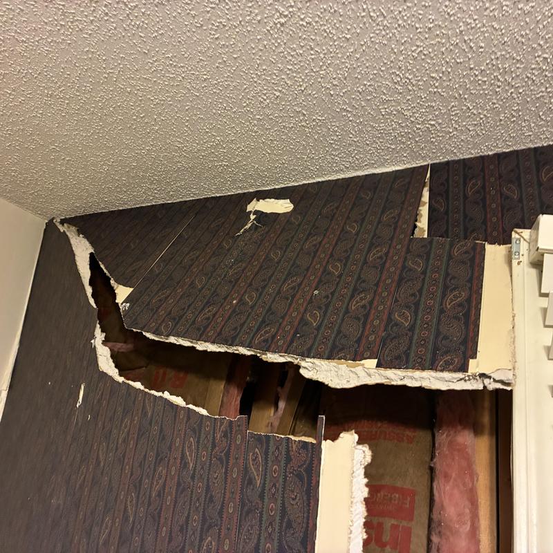 Interior drywall with large tear exposing insulation and framing