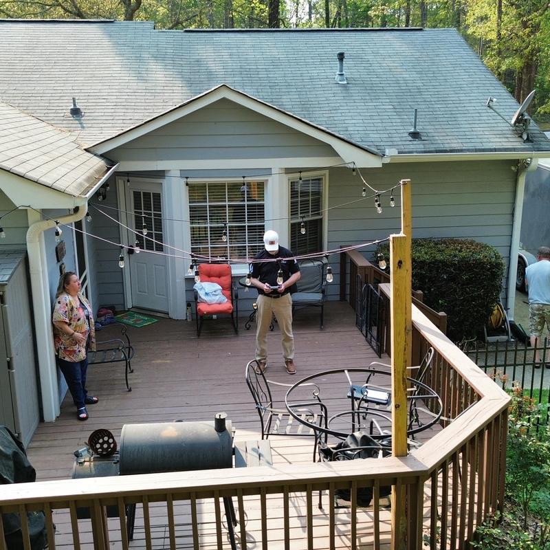 Shingle roof above wooden deck with string lights