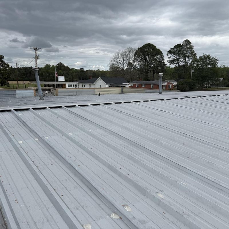 Metal roof panels on commercial building under cloudy sky