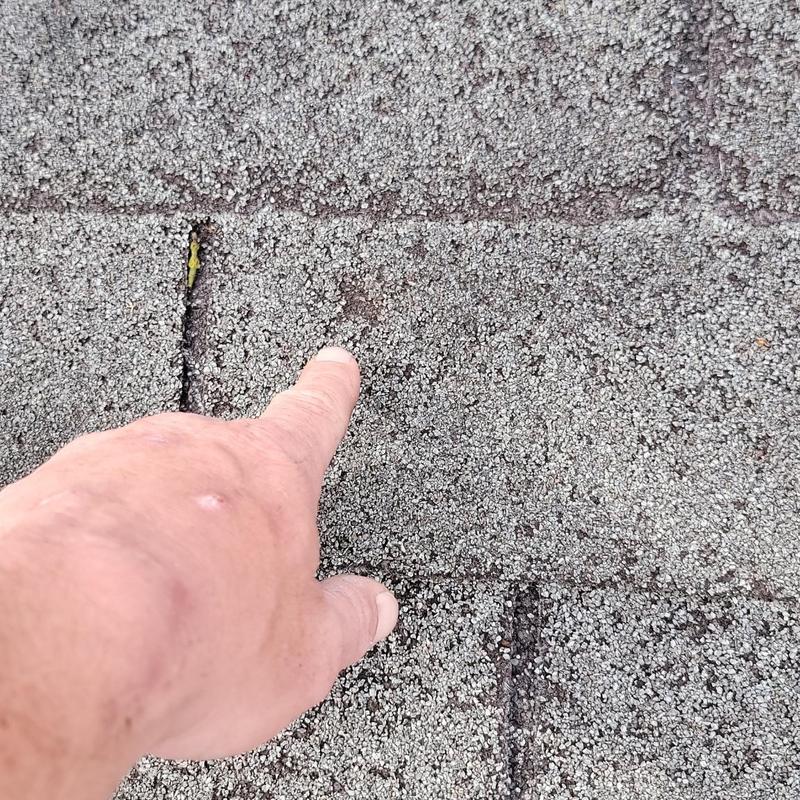 Roof shingles with hail damage being pointed at