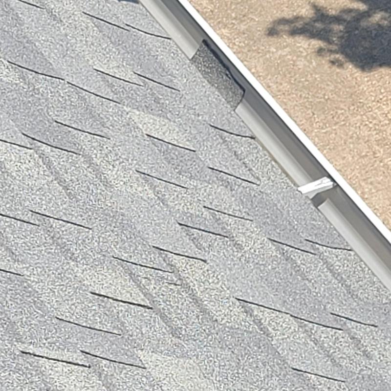 Asphalt shingles roof with visible hail damage near gutter