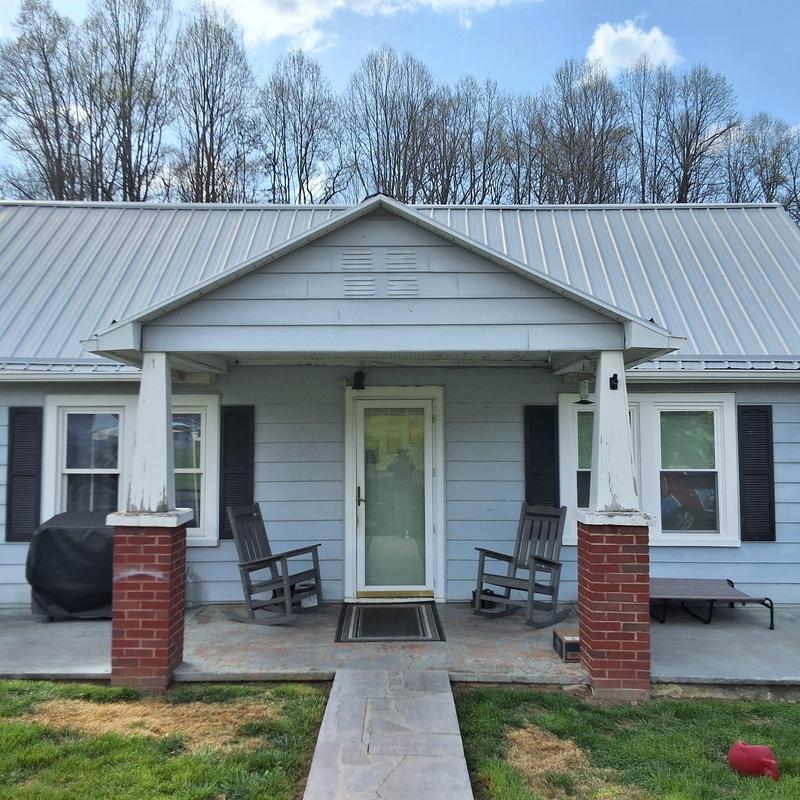 Metal roof with porch and rocking chairs at house
