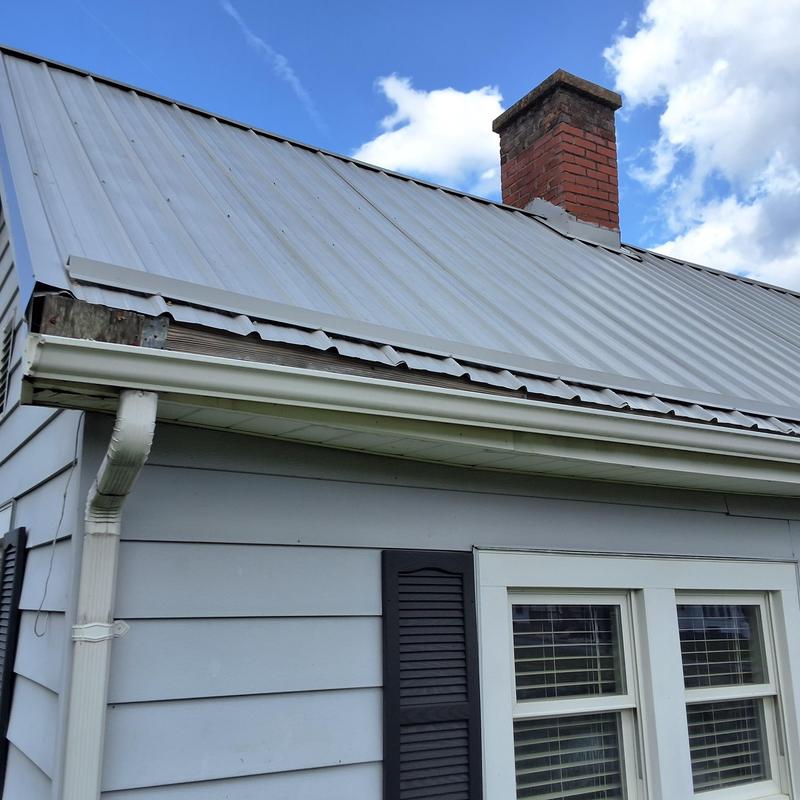 Metal roof with damaged edge near chimney and gutter