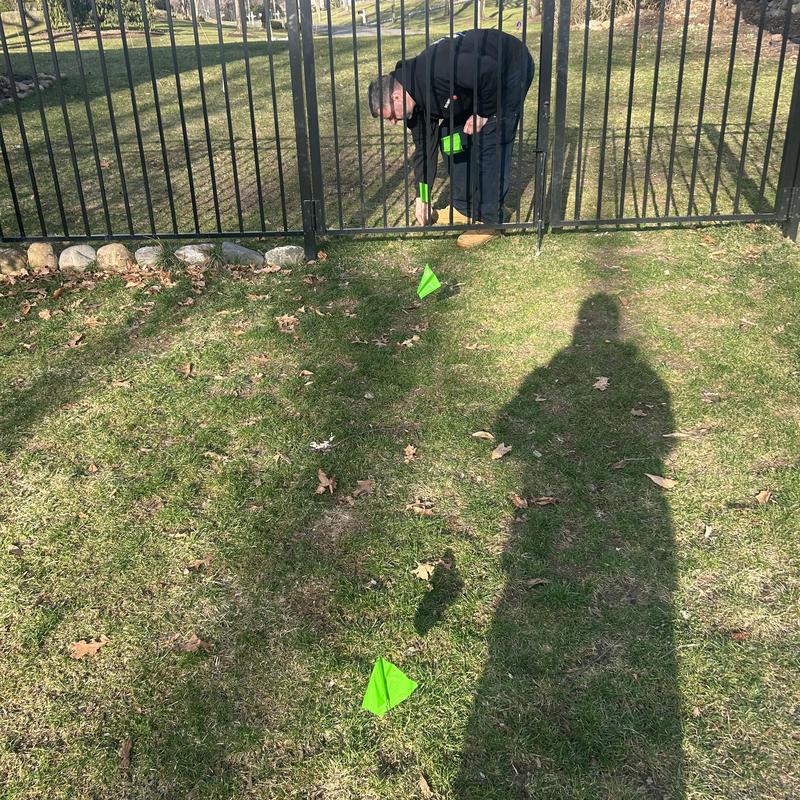 Sewer line location flags with technician marking site Sewer line location flags with technician marking site