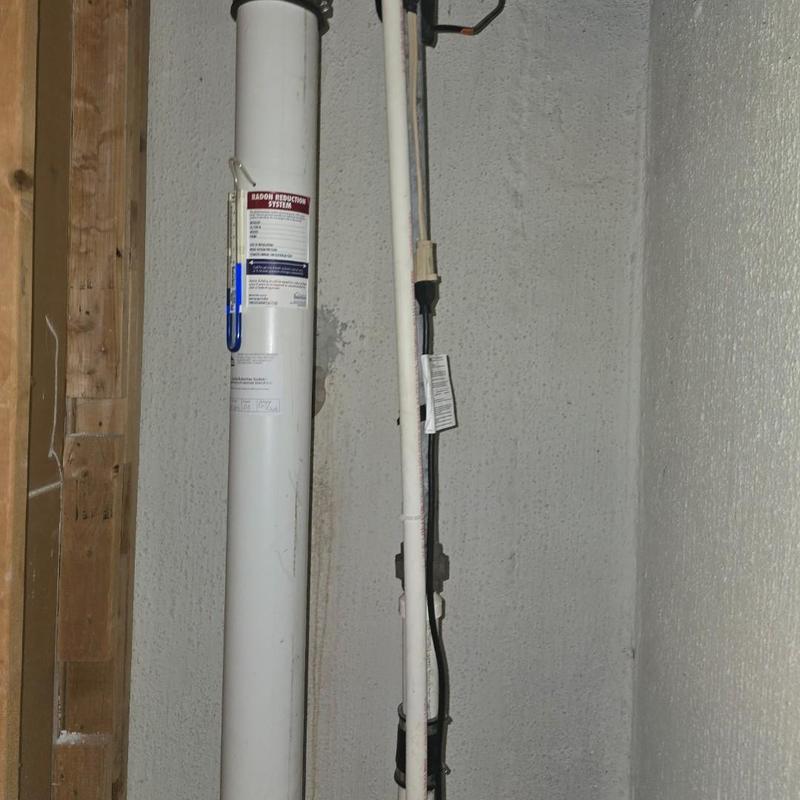 Radon reduction system pipe installation in basement wall