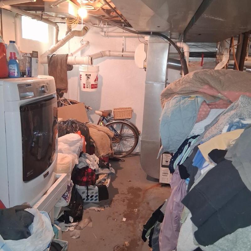 Drain pipes with laundry and clutter in basement