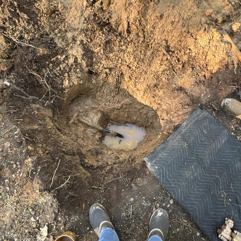 Main water line with leak and muddy excavation site