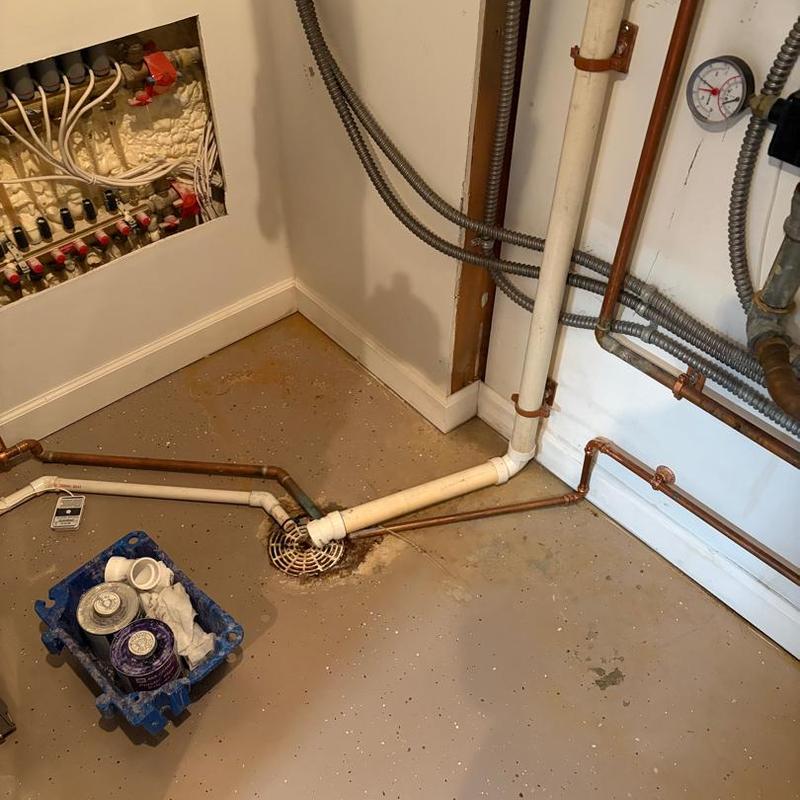 Condensate drain pipe with cleaning supplies in basement