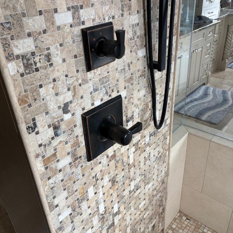Shower cartridge valve with black handles on tile wall