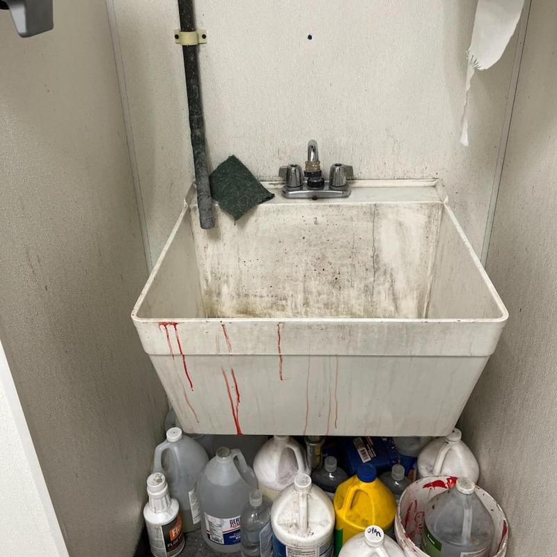 Utility sink faucet and water lines with cleaning supplies