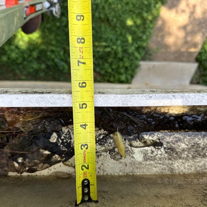 Gutter debris buildup with tape measure depth
