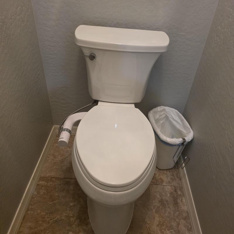 Toilet with bidet attachment installed in small bathroom
