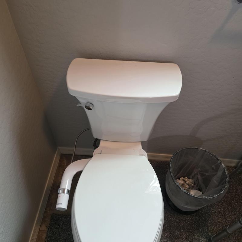Toilet with attached bidet nozzle installation in bathroom corner
