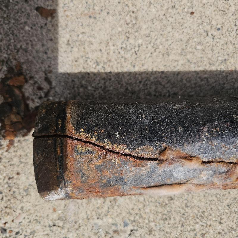 Cast iron drain pipe with visible crack and rust