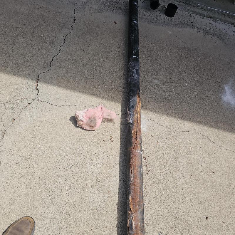 Cast iron drain pipe with corrosion and damage on concrete