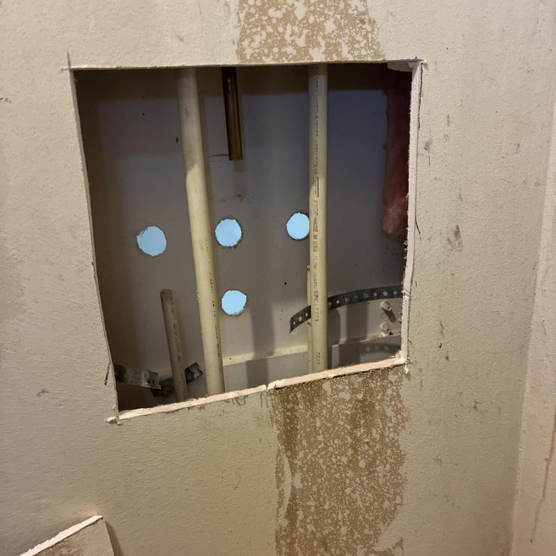 Bathroom plumbing wall access with PVC pipe holes
