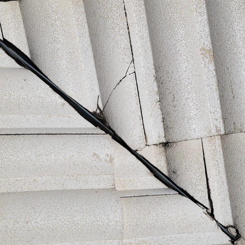 Concrete tile roof cracks at valley with visible wear