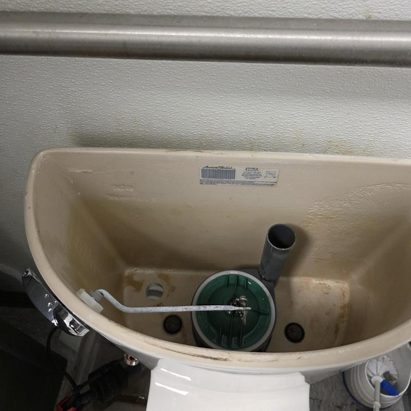 Toilet fill valve inside tank with float arm in commercial toilet