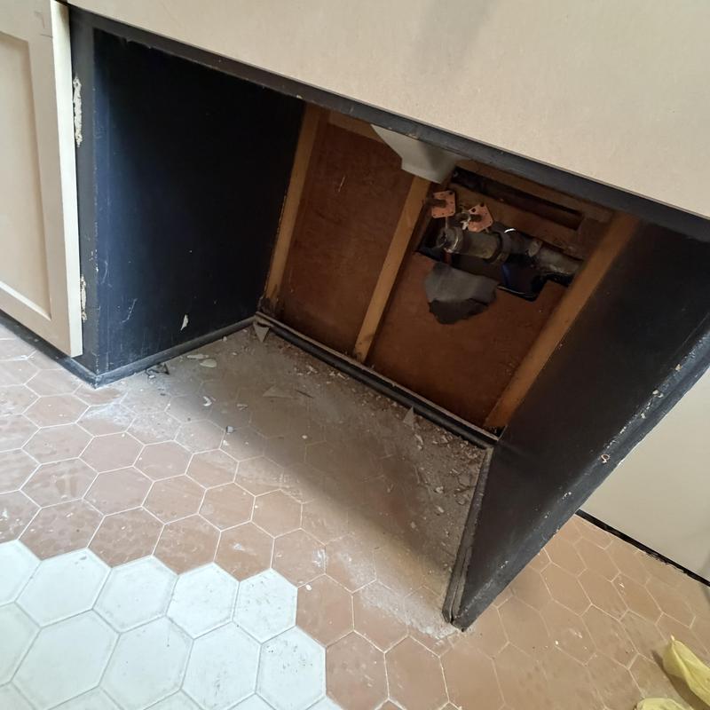 Bathroom vanity plumbing and damaged Sheetrock exposed