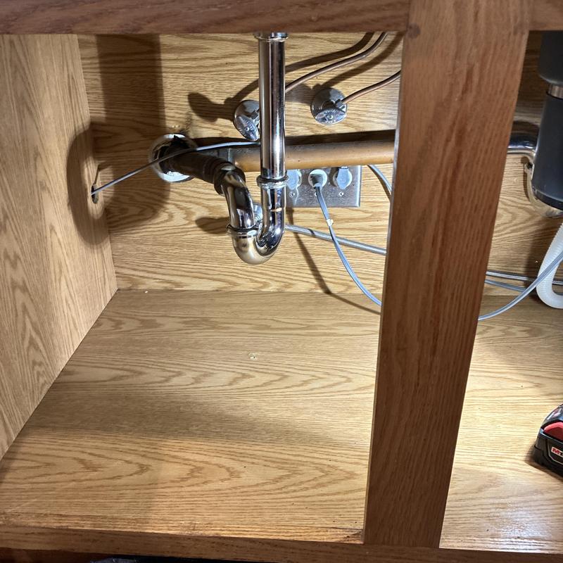 Kitchen sink drain pipes under wooden cabinet cleaned