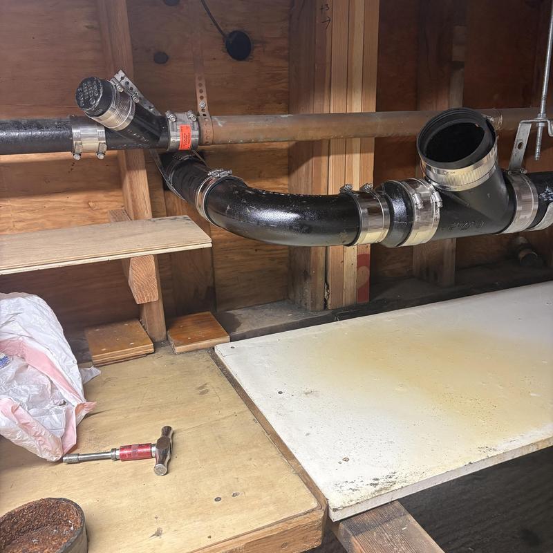 Cast iron sewer pipe with new fittings under sink