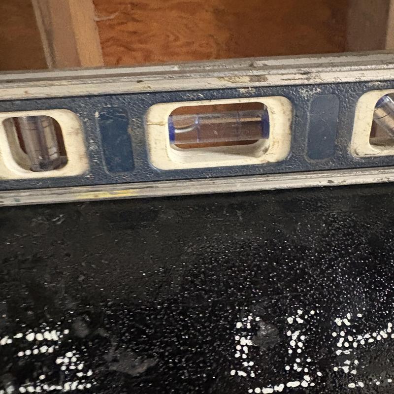 Sewer line level checked with spirit level in crawl space