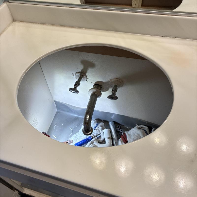 Bathroom sink cutout with faucet and plumbing tools