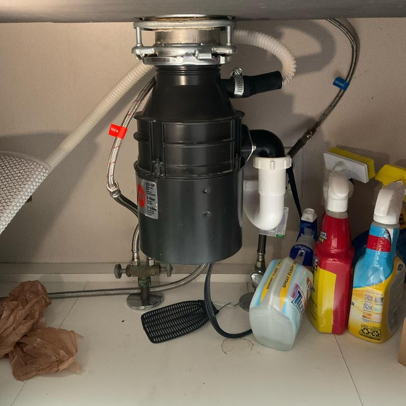 Garbage disposal unit under kitchen sink with plumbing