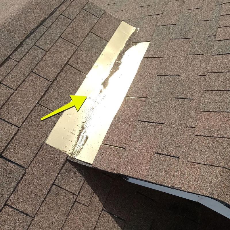 Roof flashing damage with yellow arrow on shingle roof