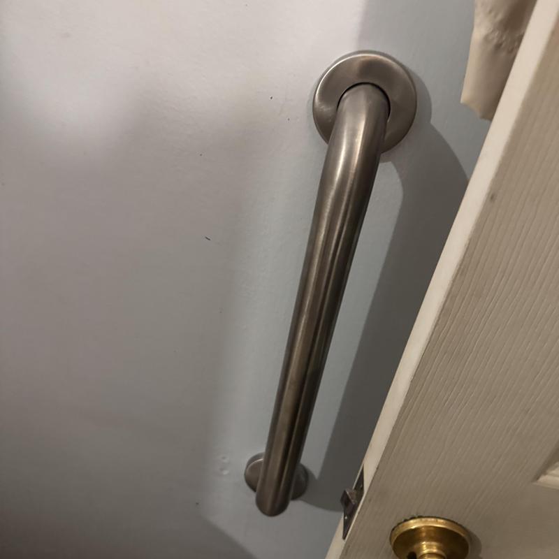 Stainless steel grab bar installation near ADA toilet door Stainless steel grab bar installation near ADA toilet door