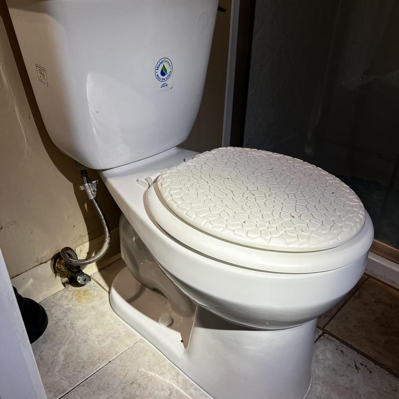 Toilet with decorative seat cover in bathroom corner Toilet with decorative seat cover in bathroom corner