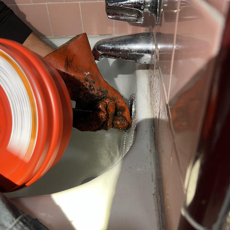 Tub drain clog removal with plumbing snake in use Tub drain clog removal with plumbing snake in use