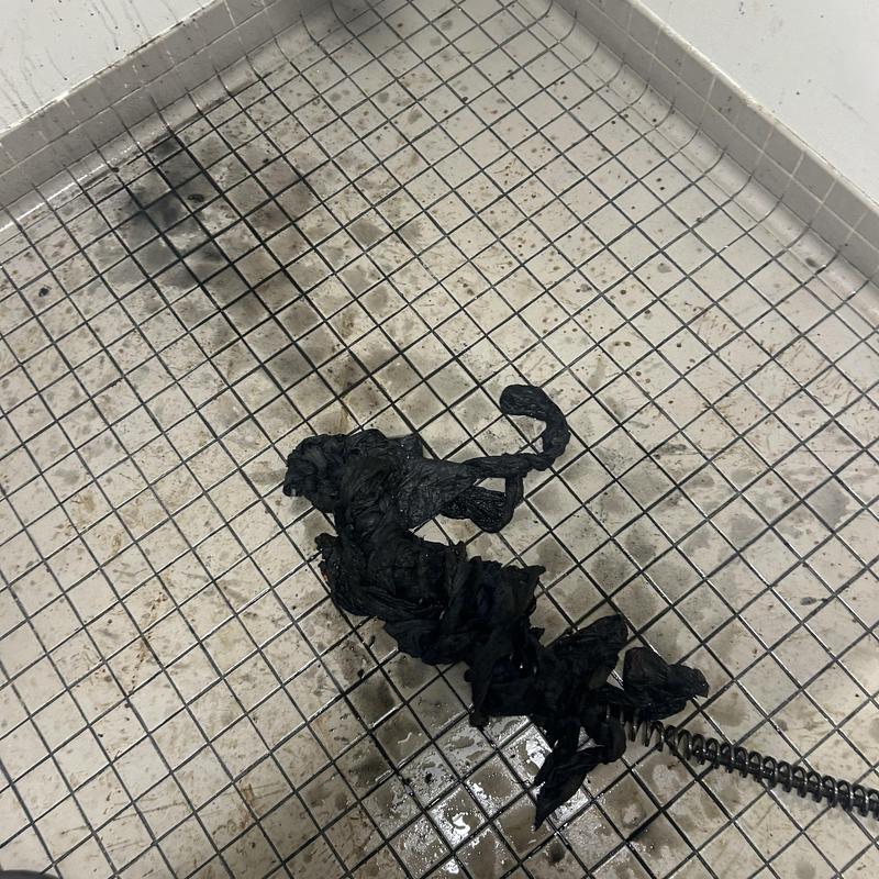 Main sewer line clog with removed debris on tile floor Main sewer line clog with removed debris on tile floor