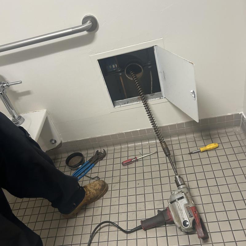 Main line sewer cleaning machine in restroom wall access panel Main line sewer cleaning machine in restroom wall access panel