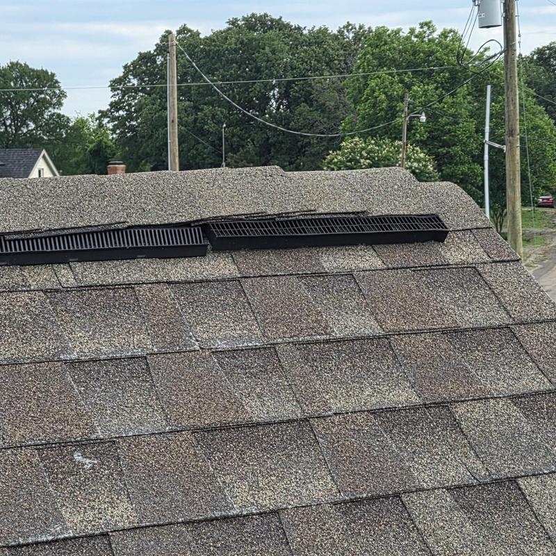 Asphalt shingle roof with hail damage near ridge vent