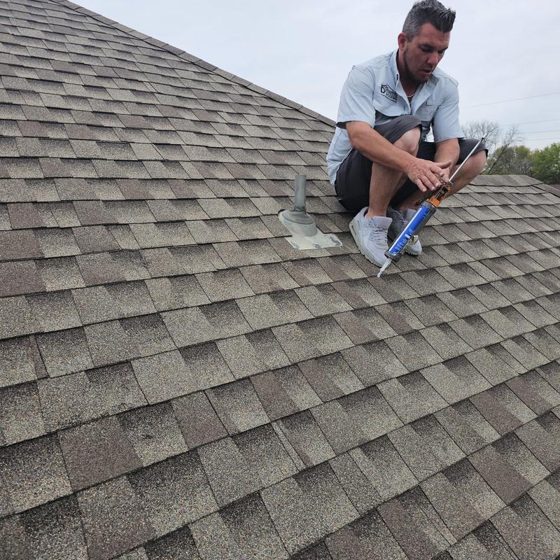 Asphalt shingle roof with technician applying sealant