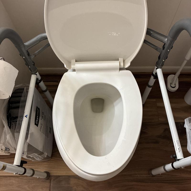 Toilet bowl with safety frame on wooden floor
