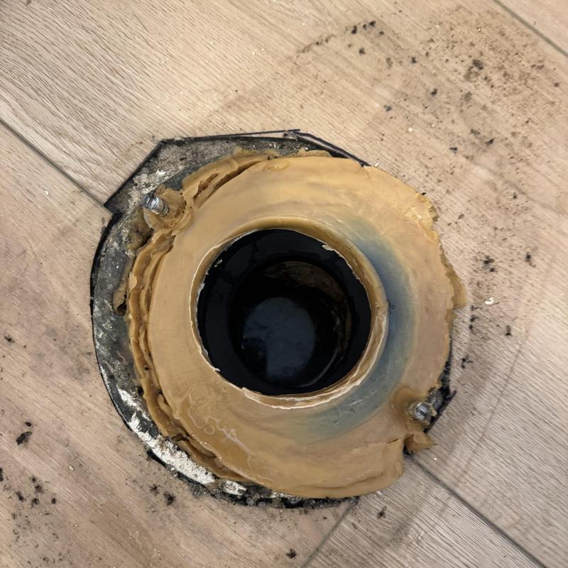 Toilet flange with old wax ring on wooden floor