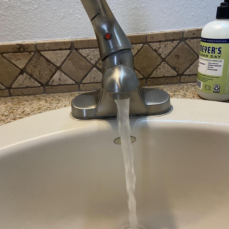 Bathroom sink faucet running water with soap bottle nearby Bathroom sink faucet running water with soap bottle nearby