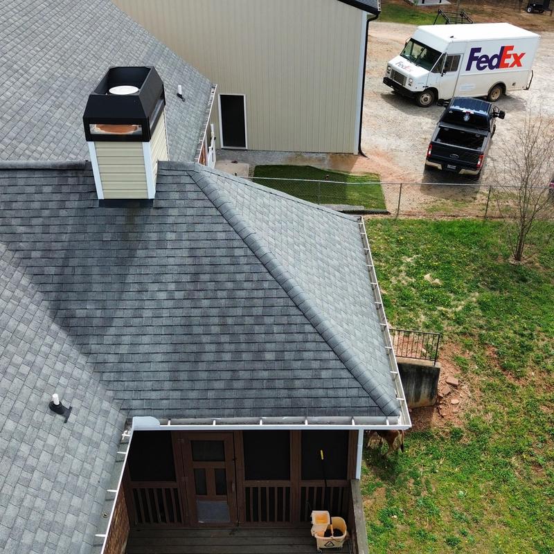 Grey asphalt shingle roof with white gutters and chimney