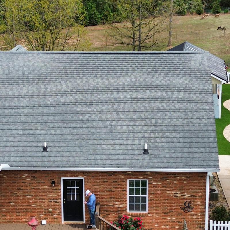 Grey asphalt shingle roof with white gutters on brick house