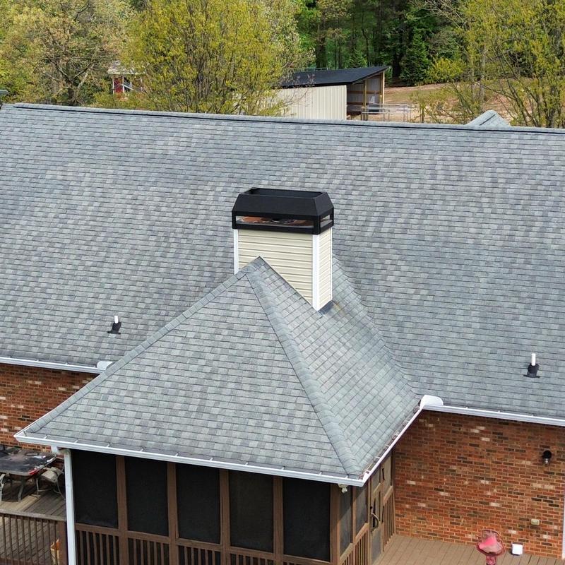 Grey asphalt shingle roof with ridge caps and white gutters